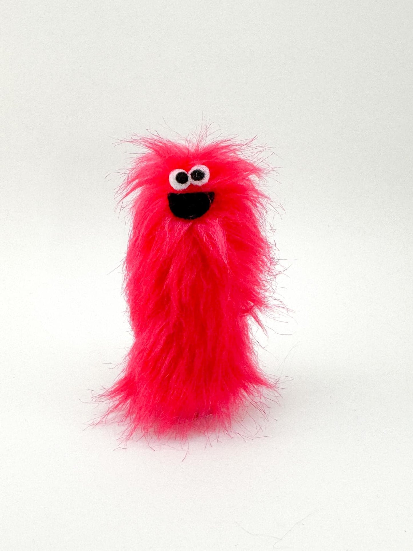 Furry and smiling monster finger puppet with multicolor UV reactive faux fur