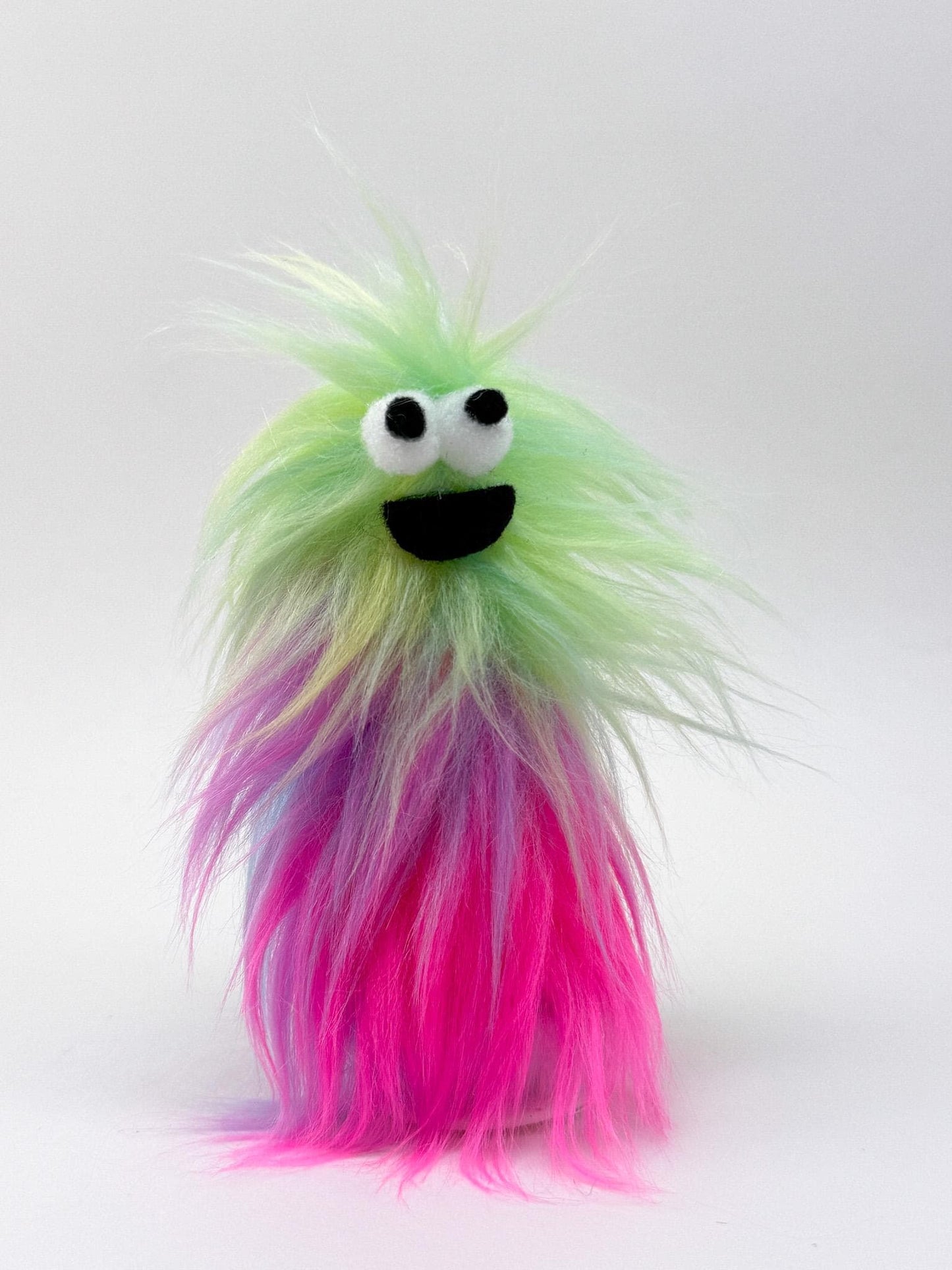 Furry and smiling monster finger puppet with multicolor UV reactive faux fur