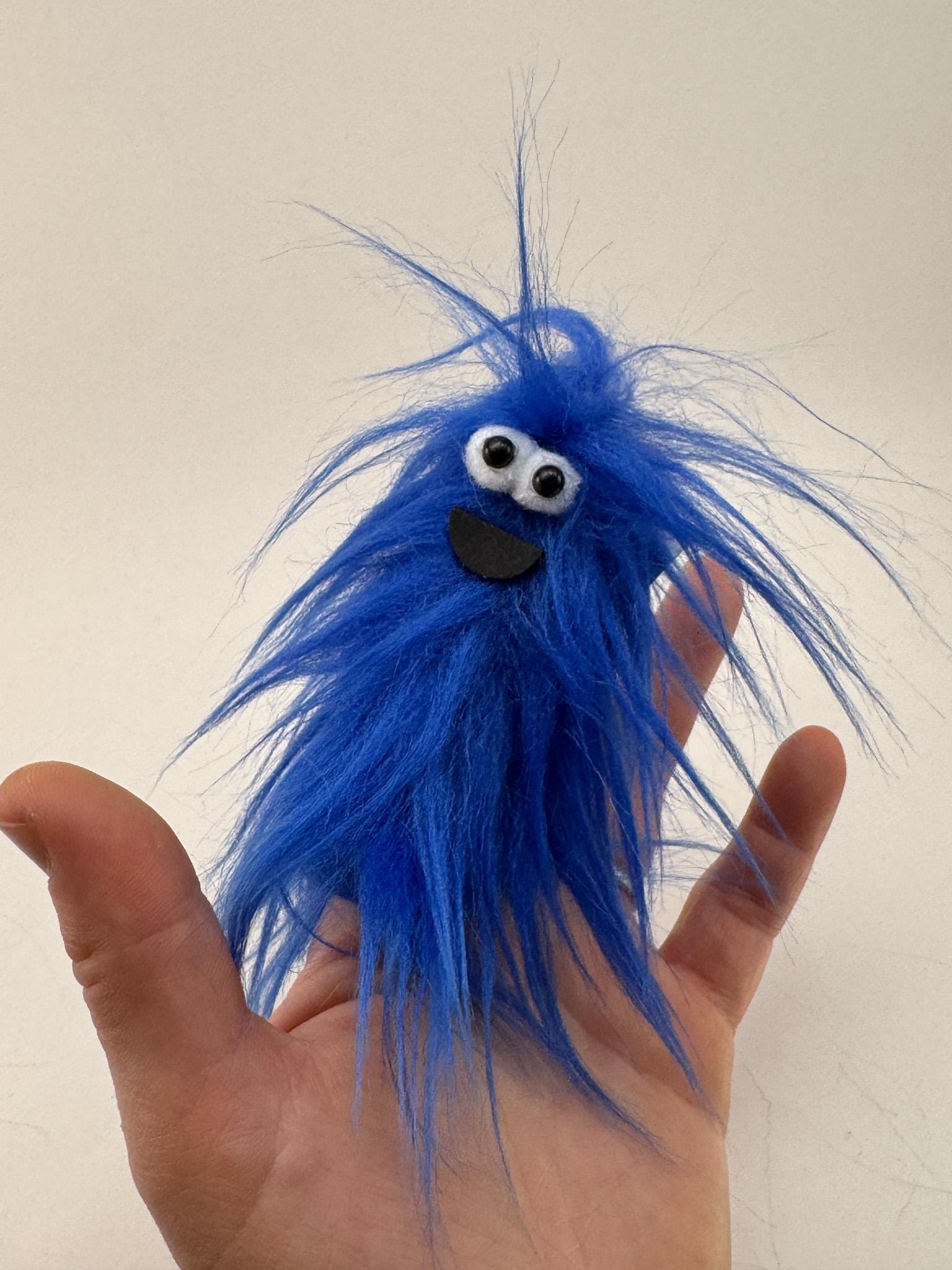 Furry and smiling monster finger puppet with multicolor UV reactive faux fur